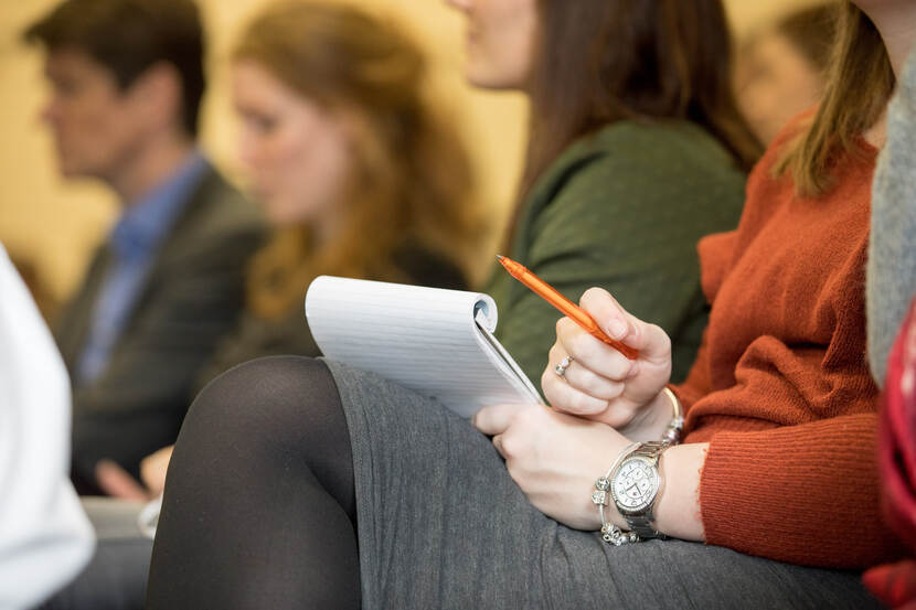 Mensen in collegezaal met notitieblok en pen