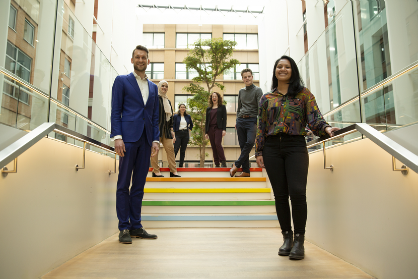 Collega's van DUS-I staan op de trap en lachen vriendelijk